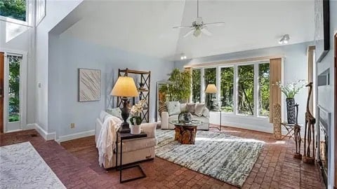 Staged living room with cream sofas, layered rug and a glass coffee table under a vaulted ceiling