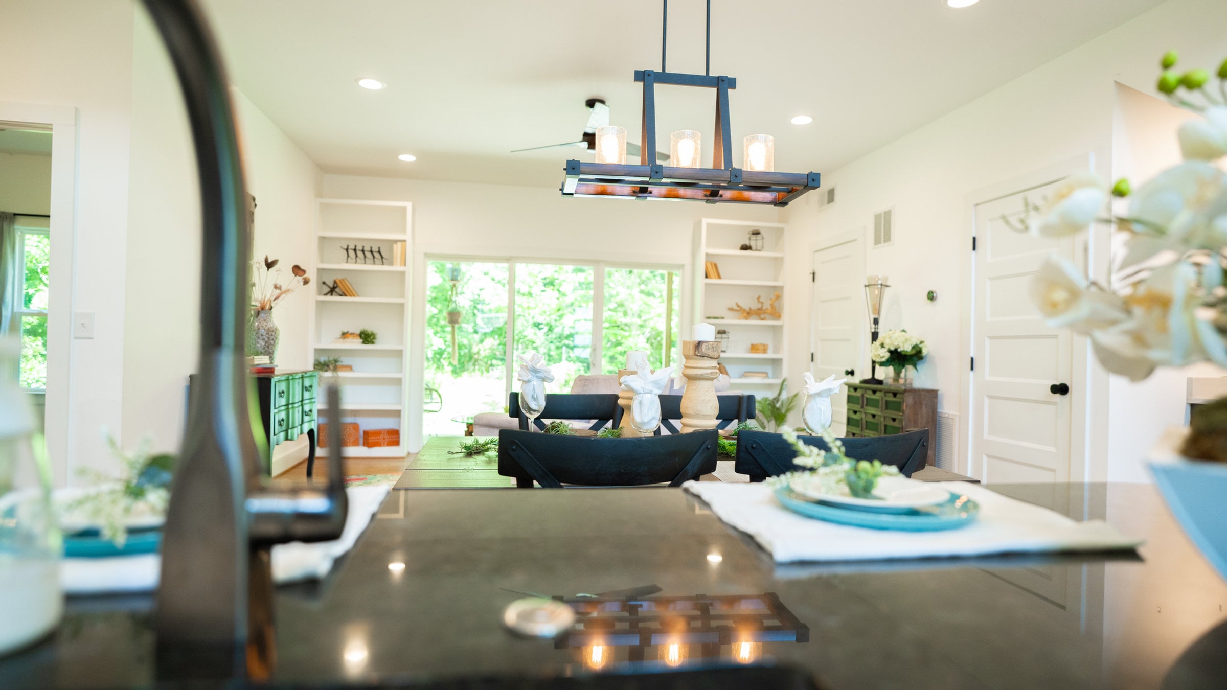 Staged open-plan kitchen and living room with a set dining table and greenery